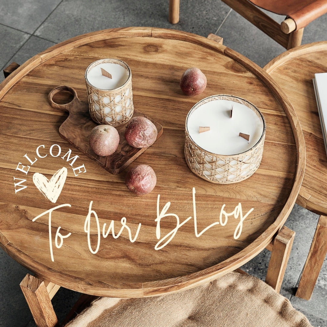 Rustic wooden serving board with scented wood wick candles and fruit on a wooden coffee table with 'Welcome to Our Blog' text, symbolising cozy home decor and lifestyle by The Mountain Merchant