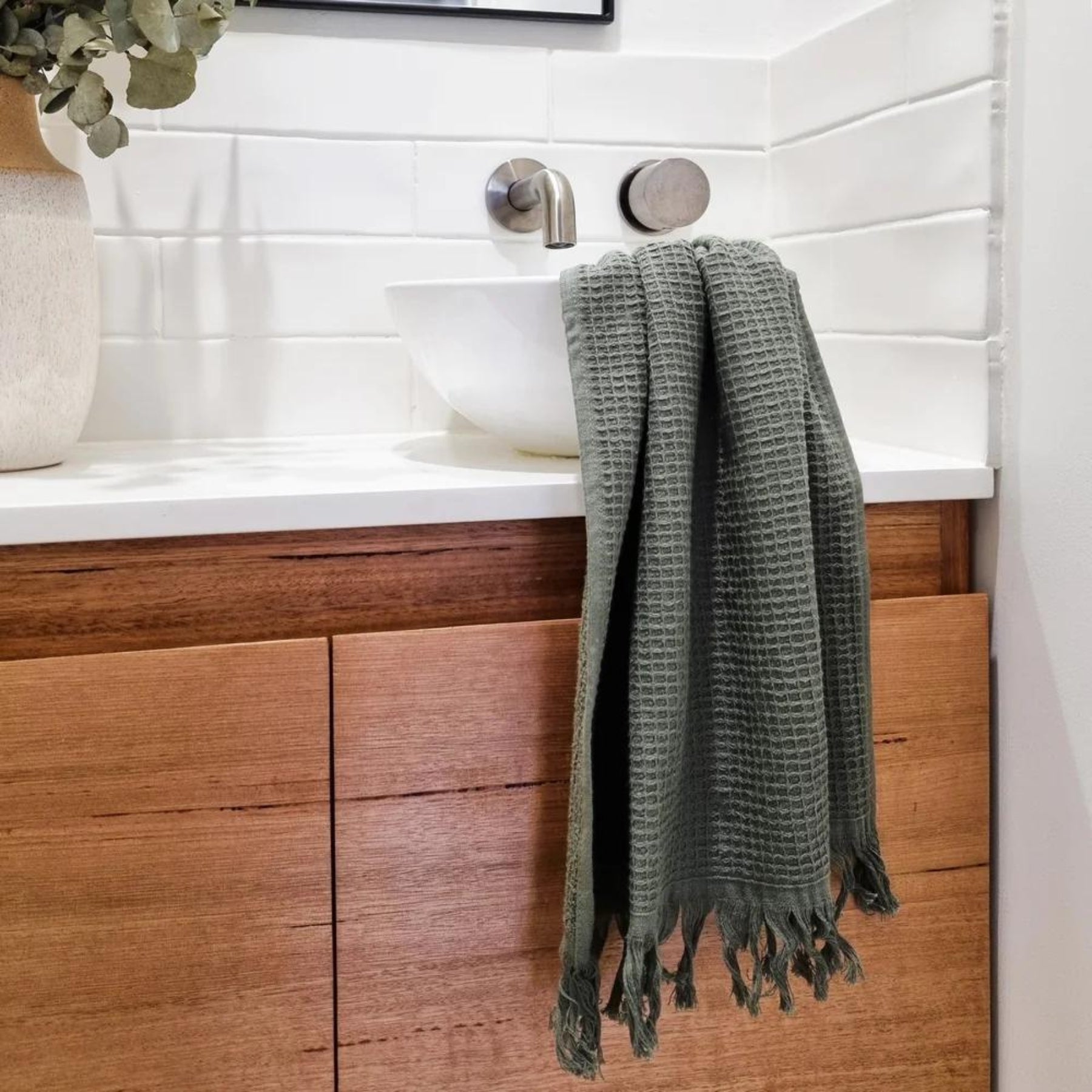 amila Cotton Waffle Hand Towels in Chive hanging gracefully in a bathroom setting, offering a rich, textured look and earthy charm.