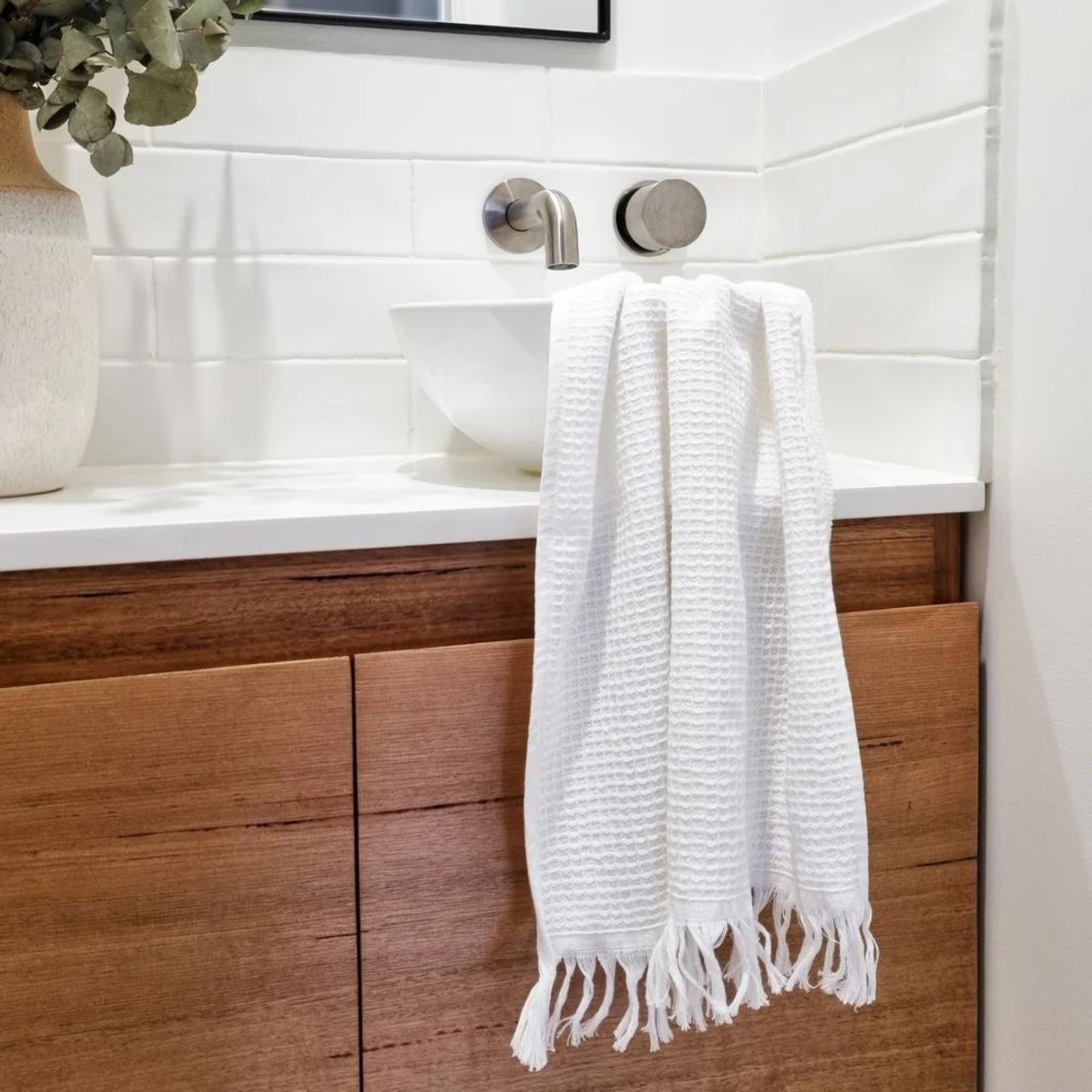 Camila Cotton Waffle Hand Towel in Cloud draped elegantly over a modern bathroom sink, offering a clean and refreshing aesthetic.