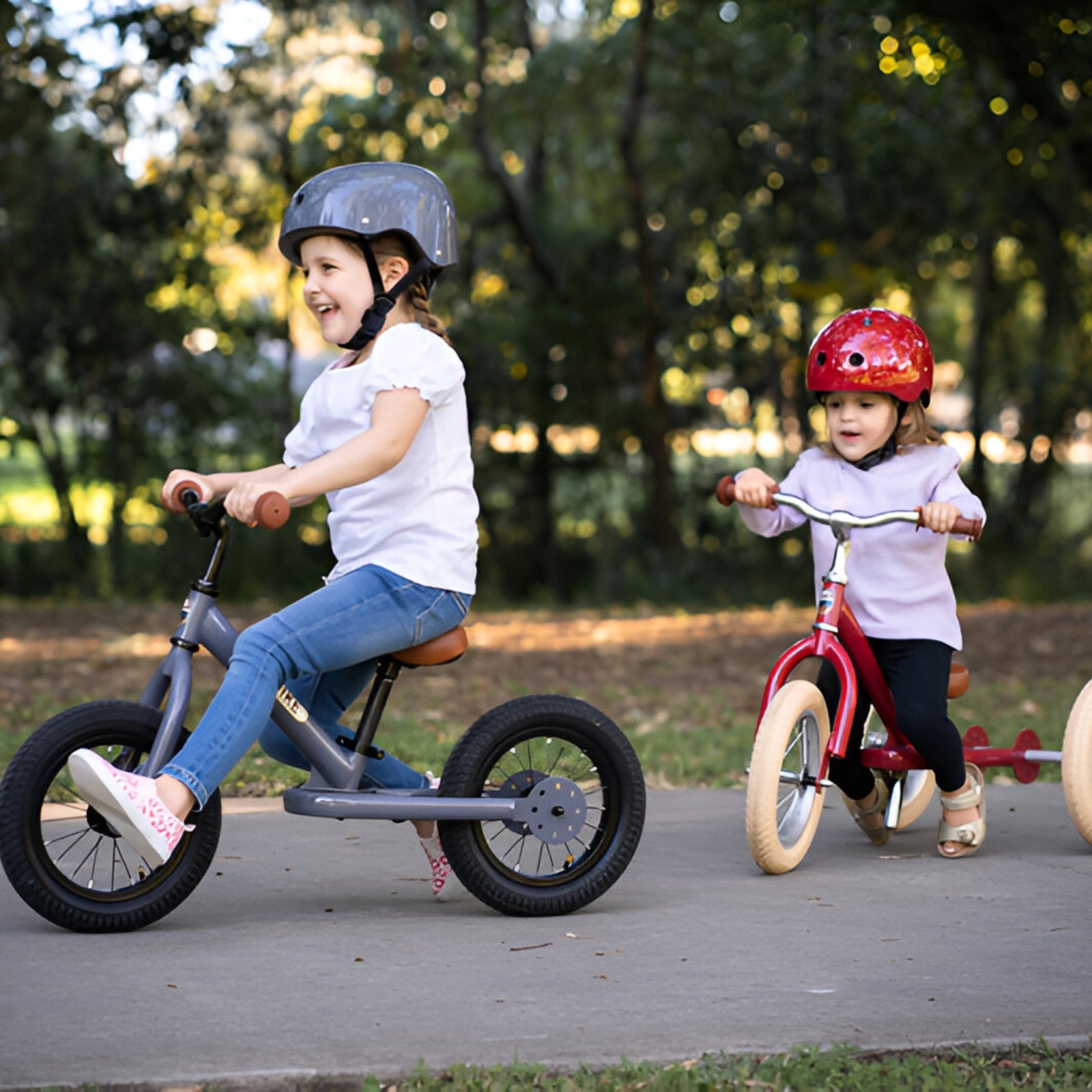 Children having fun riding a Grey Trybike and a vintage red trybike in the park.