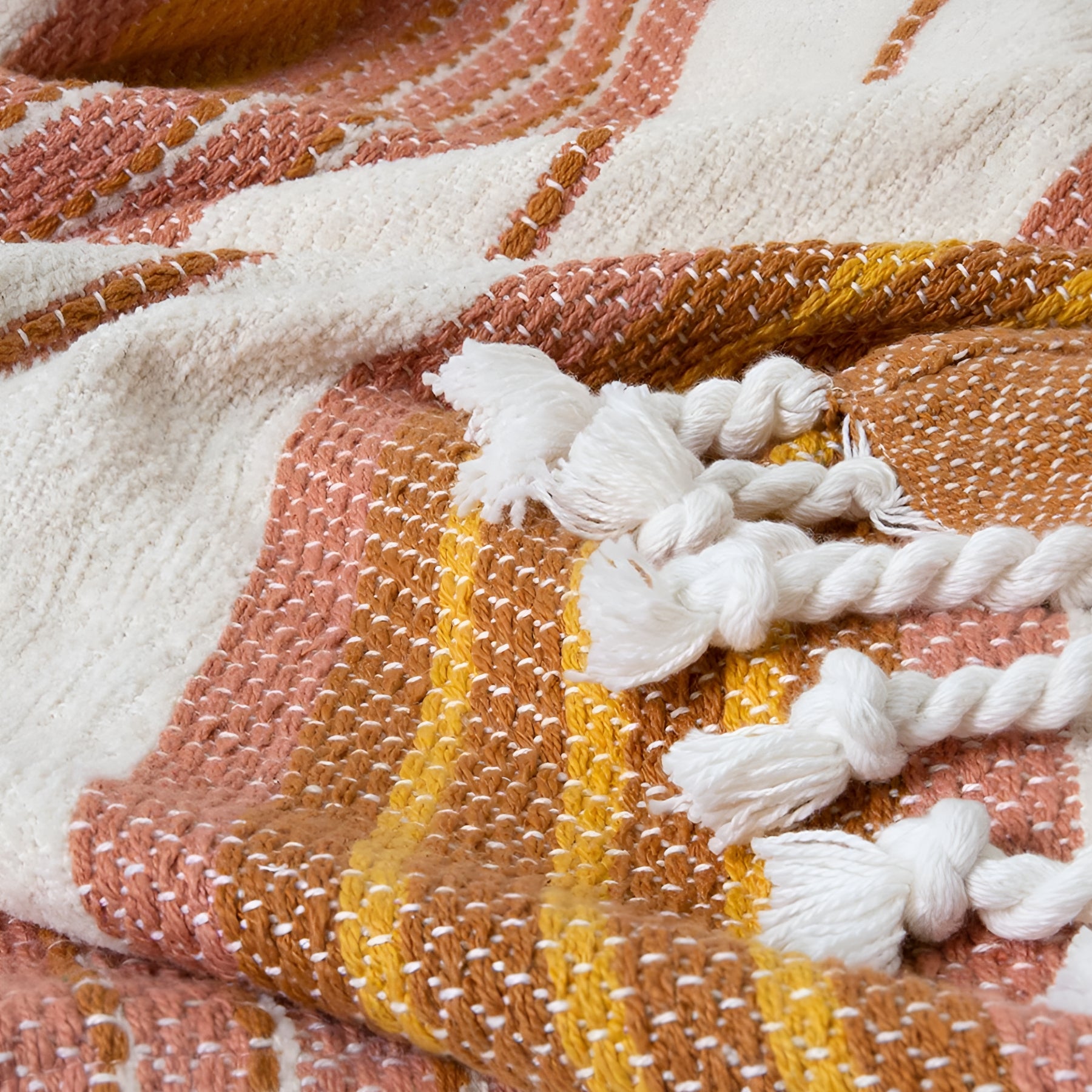 Close-up of Zephyr Peach Hues Throw with detailed stripe pattern and tassels.