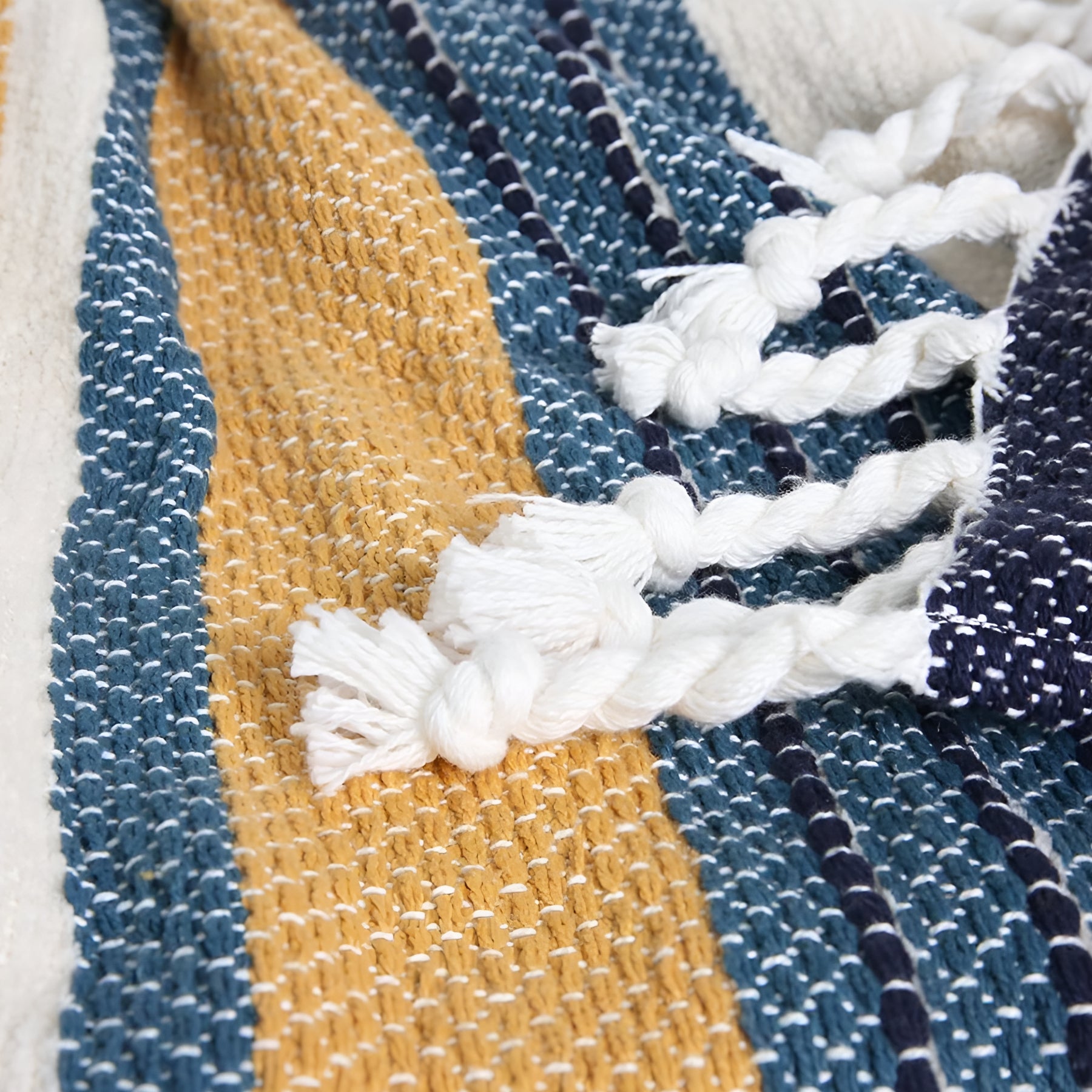 Close-up of the Zephyr striped throw in Blue Hues, focusing on the plush tassels and vibrant stripe pattern.